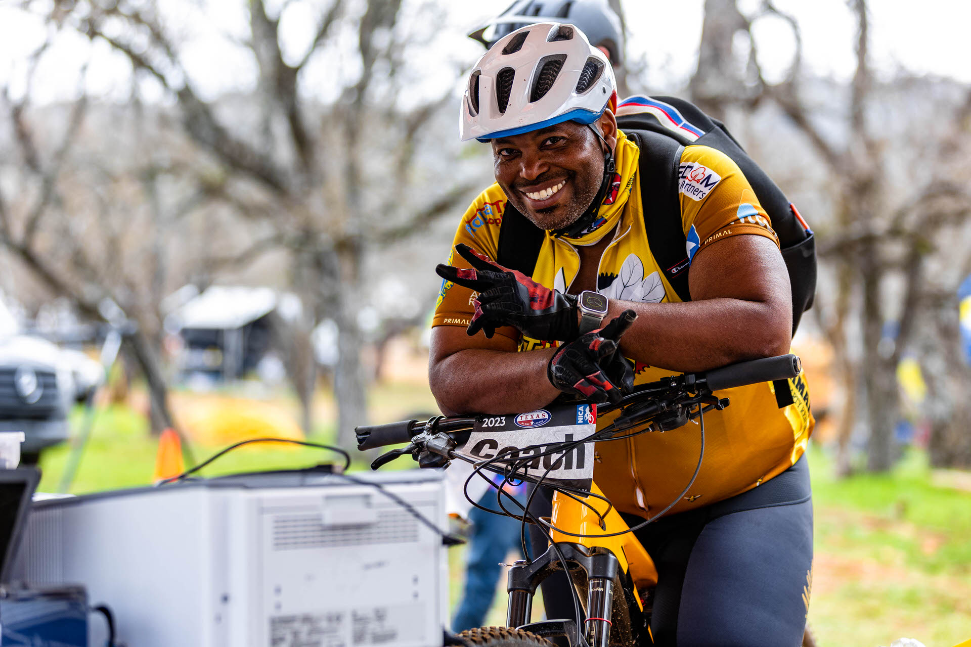 Coach on a mountain bike giving a peace sign